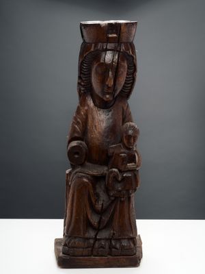 une vieille statue en bois représentant une femme assise sur une chaise