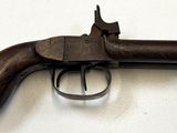 un vieux pistolet avec une poignée en bois sur une surface blanche