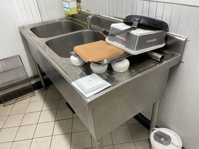 a kitchen sink with a cutting board on the top of it