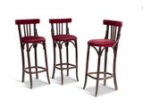 trois tabourets de bar rouges placés les uns à côté des autres sur une surface blanche