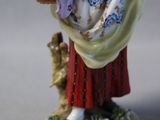a figurine of a woman holding a basket of flowers