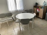 une table et des chaises blanches dans une petite pièce