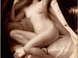 une vieille photo en noir et blanc représentant une femme nue assise sur un lit