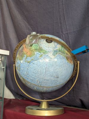 un grand globe terrestre posé sur un socle, avec une vitrine en verre devant