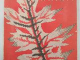 an old book with a red cover and a leaf on it