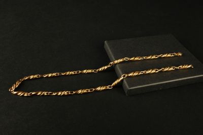 un collier à chaîne dorée présenté dans un coffret noir