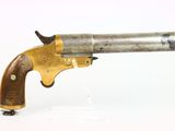 gros plan d'un pistolet avec un manche en bois sur une surface blanche