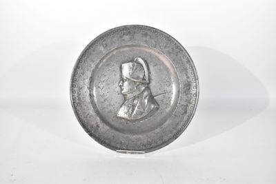 une vieille assiette en argent sur laquelle figure le portrait d'un homme