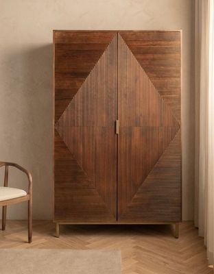 Le meuble en bois se trouve à côté d'une chaise blanche dans une pièce