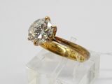 une bague de fiançailles en or sertie d'un diamant posé sur un bloc d'acrylique transparent