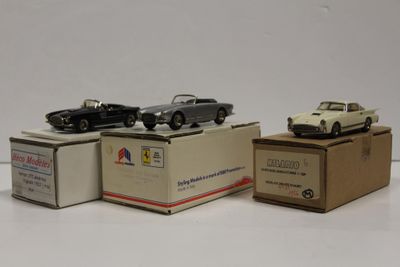 trois petites voitures posées sur des cartons, sur une surface blanche