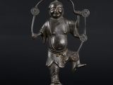 une statue en bronze représentant un homme tenant une épée et un poisson