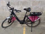 un vélo rose garé sur un parking, près d'un mur