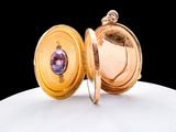 a gold locke with a purple stone inside of it