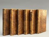 quatre vieux livres sont alignés les uns à côté des autres sur une surface grise