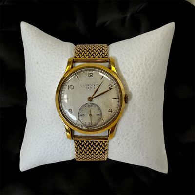 une photo d'une montre-bracelet en or posée sur un oreiller