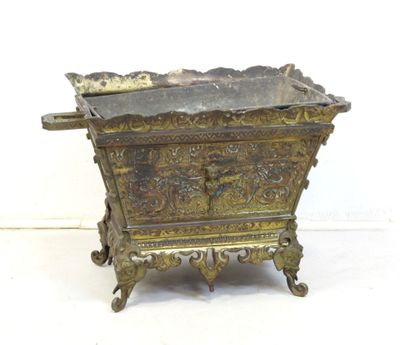 jardinière en laiton ancien avec un motif ouvragé, posée sur un socle, sur fond blanc