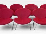 six red chairs are arranged in a circle on a white surface