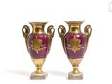 une paire de vases violets et dorés posés sur une surface blanche