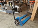 a man standing next to a blue hand truck in a garage
