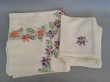 trois serviettes de table ornées de fleurs brodées, posées sur une table