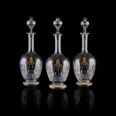 trois bouteilles en verre transparent ornées de touches dorées, posées sur un fond noir