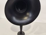 a black horn on a stand next to a white wall