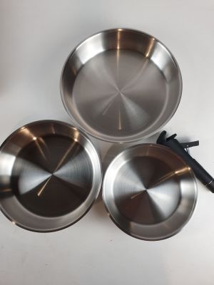 three stainless steel pans sitting on top of a white table