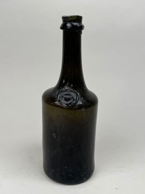 une bouteille en verre brun avec un bouchon noir posée sur une surface blanche