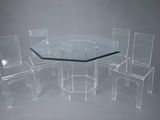 une table en verre entourée de quatre chaises, sur fond gris
