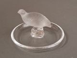 a glass bird sitting on top of a glass plate