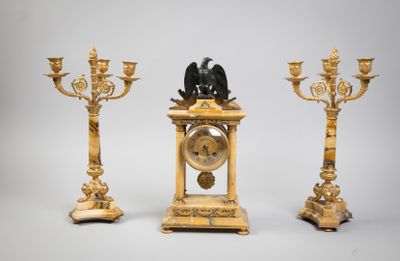 trois bougeoirs dorés et une horloge surmontée d'un oiseau