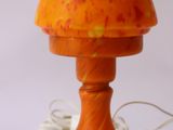 une lampe en forme de champignon orange posée sur une table blanche