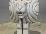 sculpture représentant une tête de lion avec un cure-dent qui dépasse de sa gueule