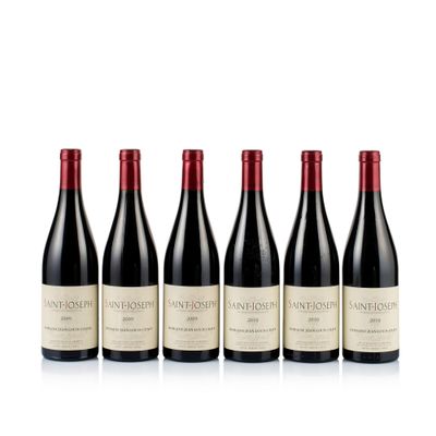 four bottles of wine are lined up on a white surface