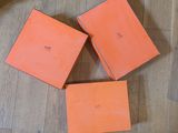 trois livres orange posés sur un plancher en bois, à côté d'un chat