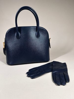 a blue handbag and gloves sitting on top of a table