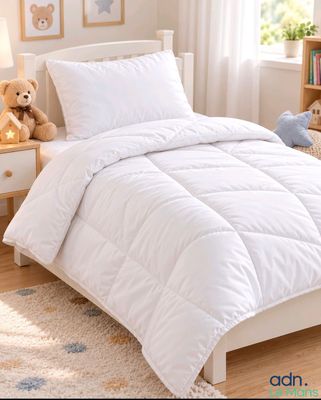 a bed with a white comforter and a teddy bear