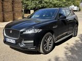 the black jaguar suv is parked in front of a hay bale
