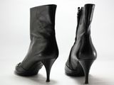 une paire de bottes en cuir noir à talons hauts sur fond blanc