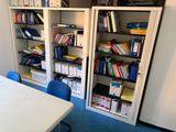 a room with a table, bookshelf, and a chair in it