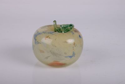 une pomme en verre surmontée d'une feuille verte