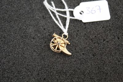 a gold necklace with a bird on it on a black surface