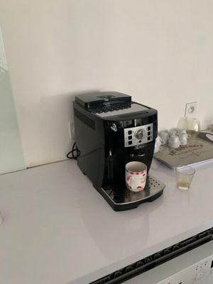 une cafetière posée sur un plan de travail, avec une tasse dessus