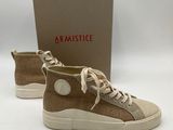 une paire de baskets beiges avec des lacets blancs et une boîte
