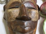 un masque en bois posé sur une table à côté d'assiettes