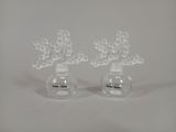 two clear vases with flowers in them on a white surface