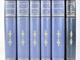 six livres bleus aux tranches dorées sont alignés sur une surface blanche