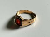 a close up of a gold ring with a red stone on it