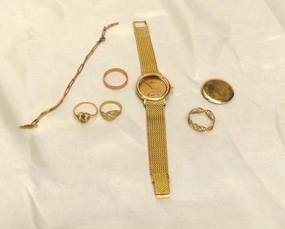 a gold wrist watch, ring, and other jewelry on a white sheet